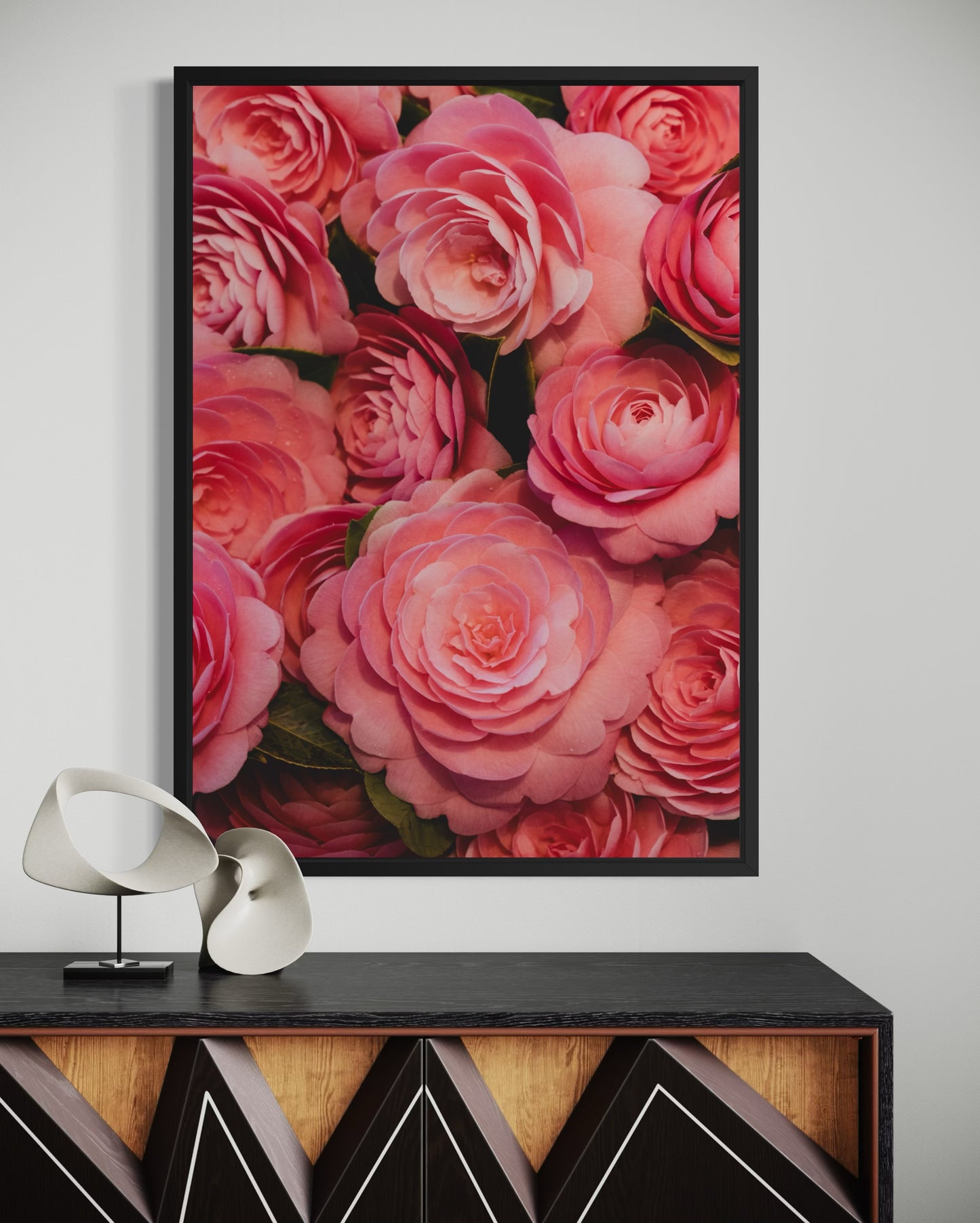 Framed pink Camellia photography print on a wall above a decorative console table.